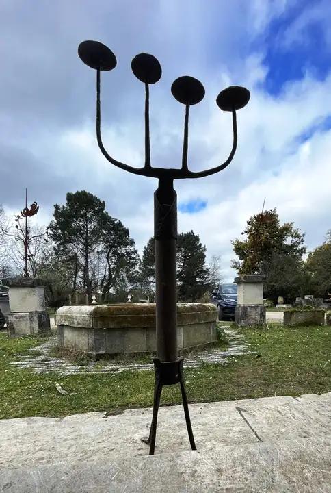 Pique-cierge en fer forgé composé à partir d'une vieille fourche et d'un manche en bois posé sur trois pieds en fer